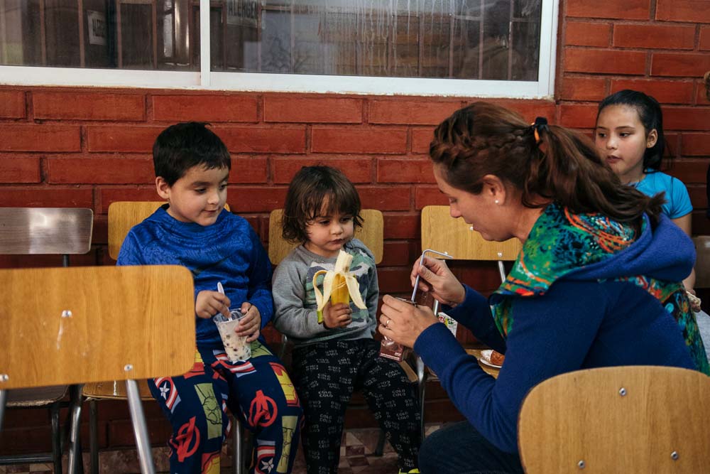 Voluntaria compartiendo la once con dos niños
